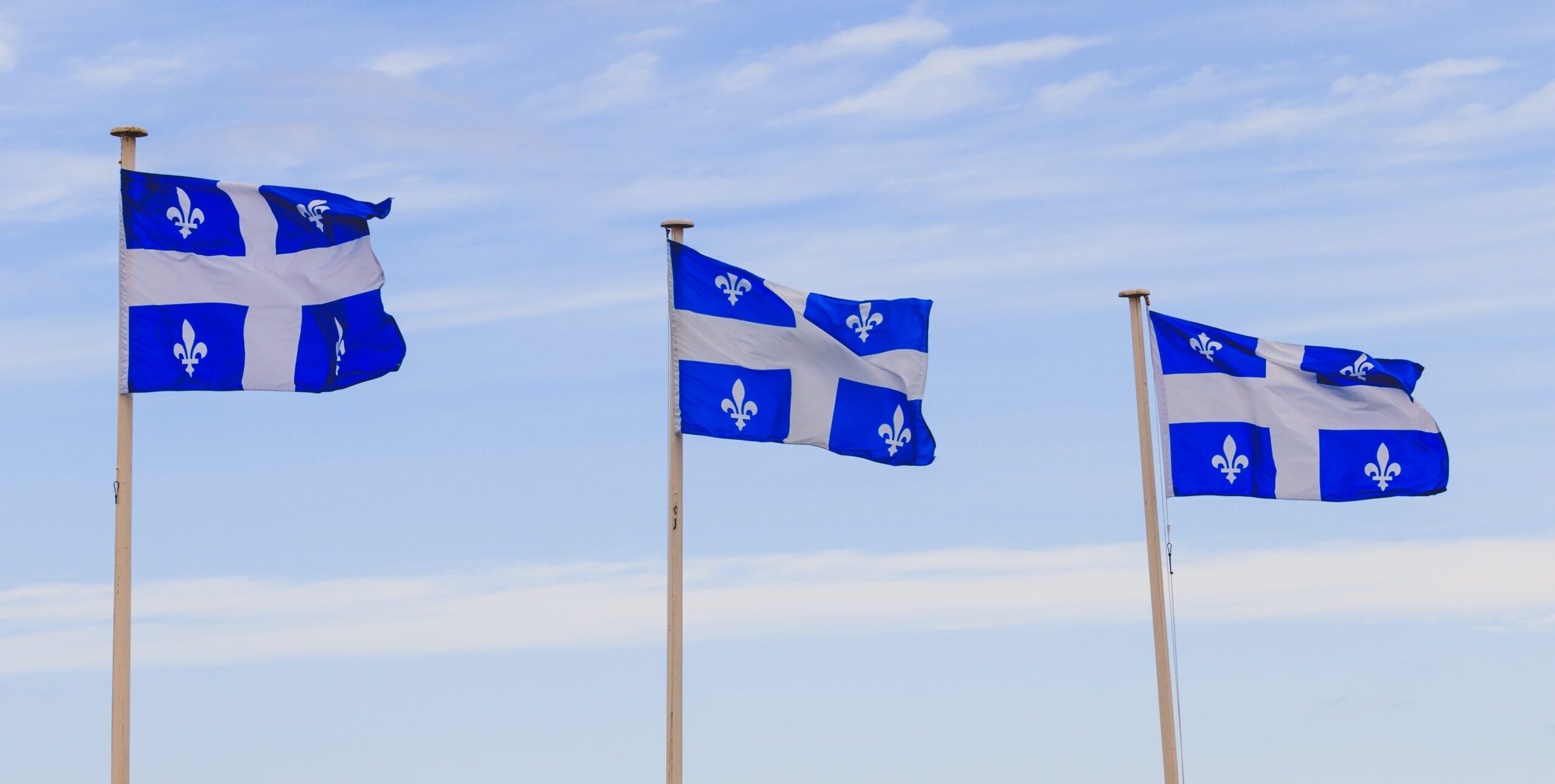 trois drapeaux du québec flottant au vent