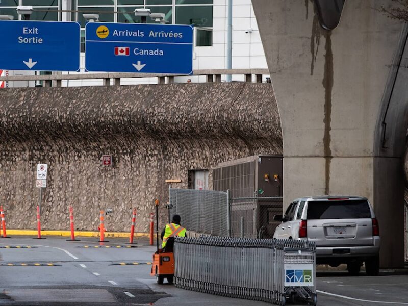 Un travailleur déplace des chariots à bagages à l'extérieur de l'aéroport international de Vancouver. LA PRESSE CANADIENNE/Darryl Dyck.